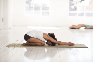 woman doing meditative yoga on a yoga mat in a white studio