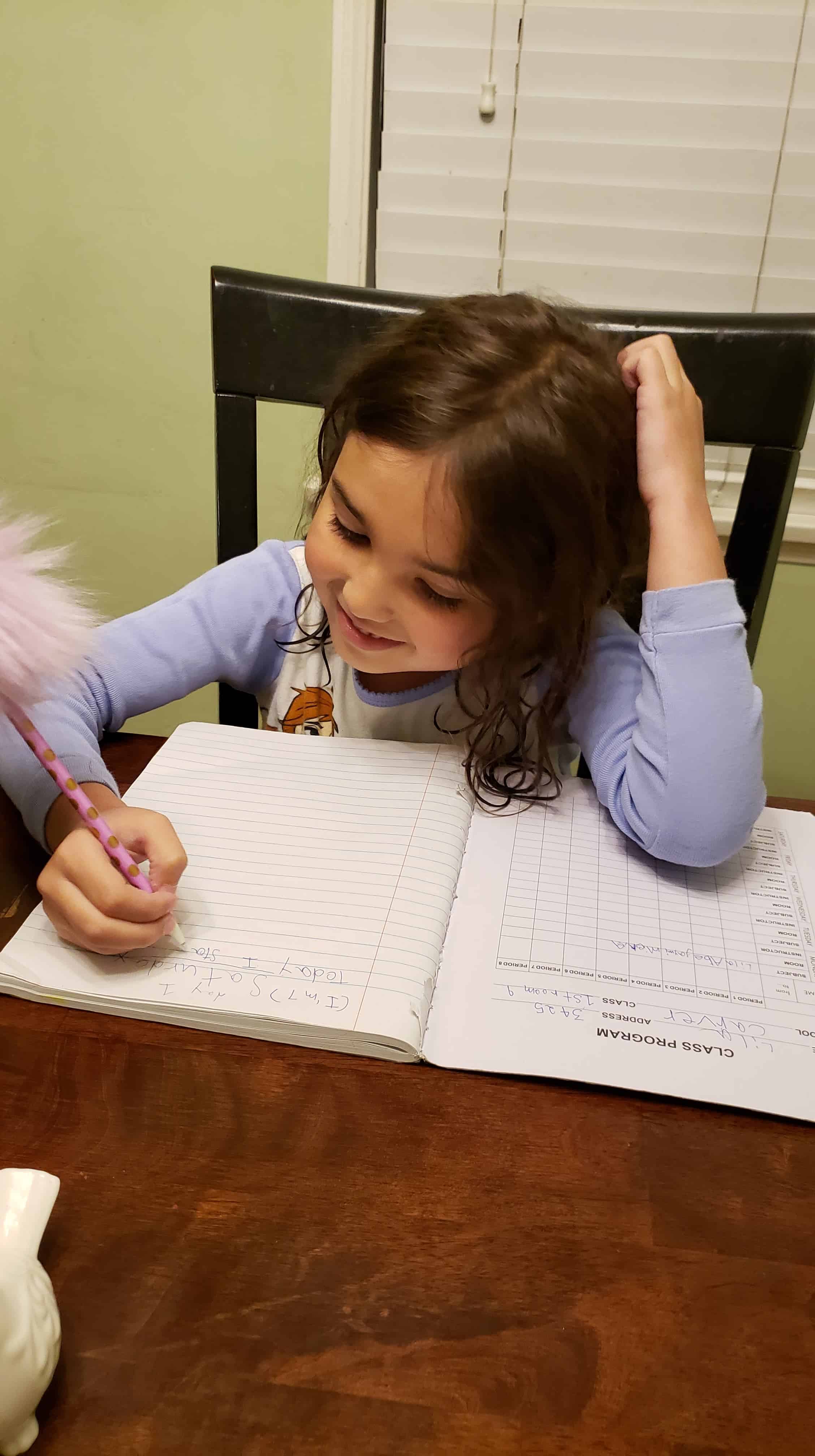 Little girl writing in a composition notebook.