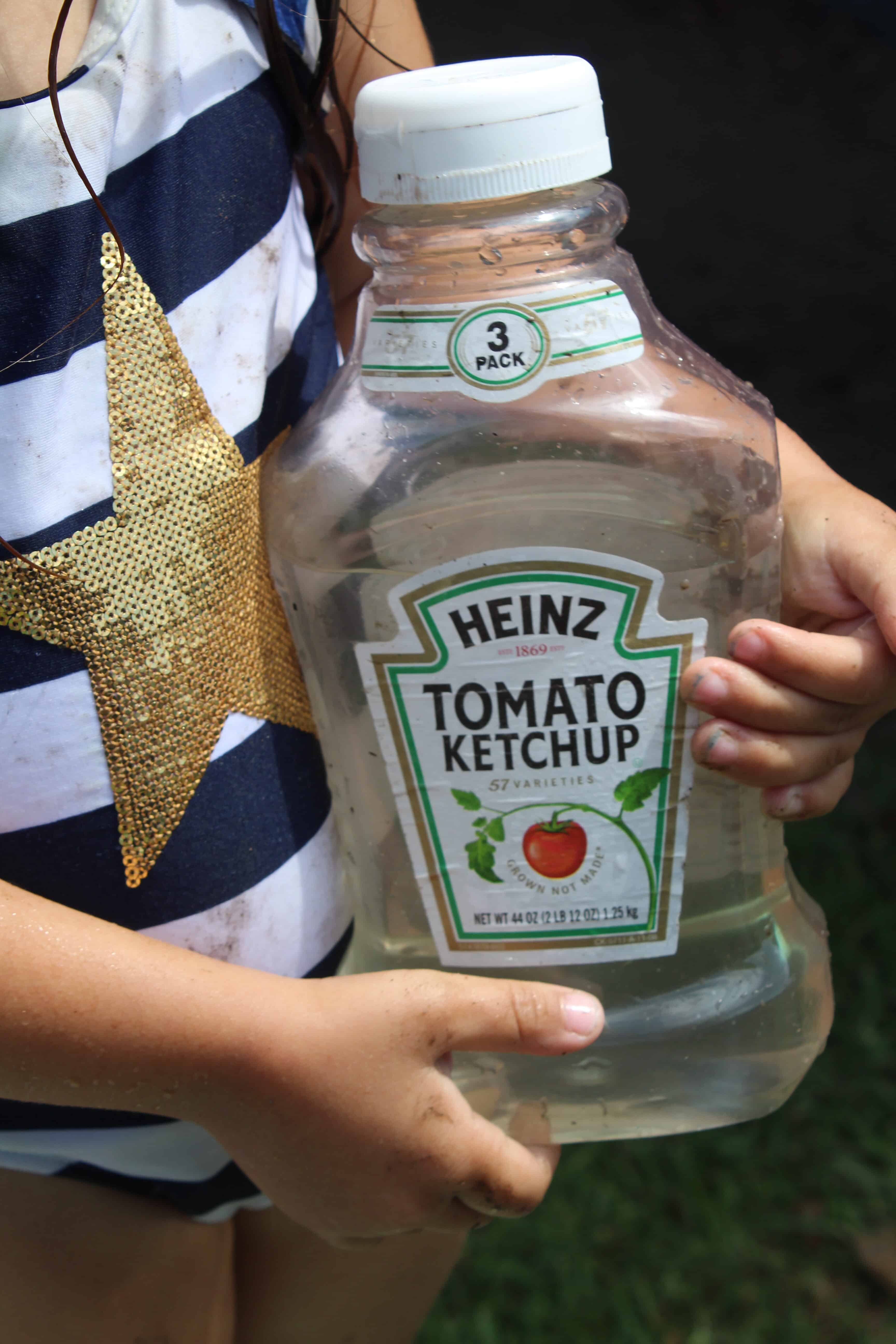 Little girl holding a recycled ketchup bottle