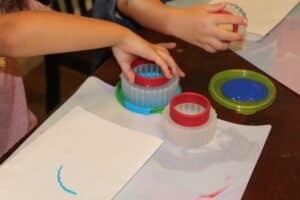 kids dipping cookie cutters in paint to use like stamps