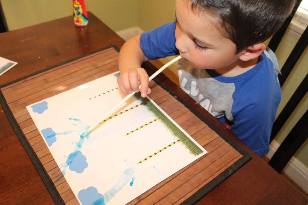 toddler using a straw to make paint truffula trees