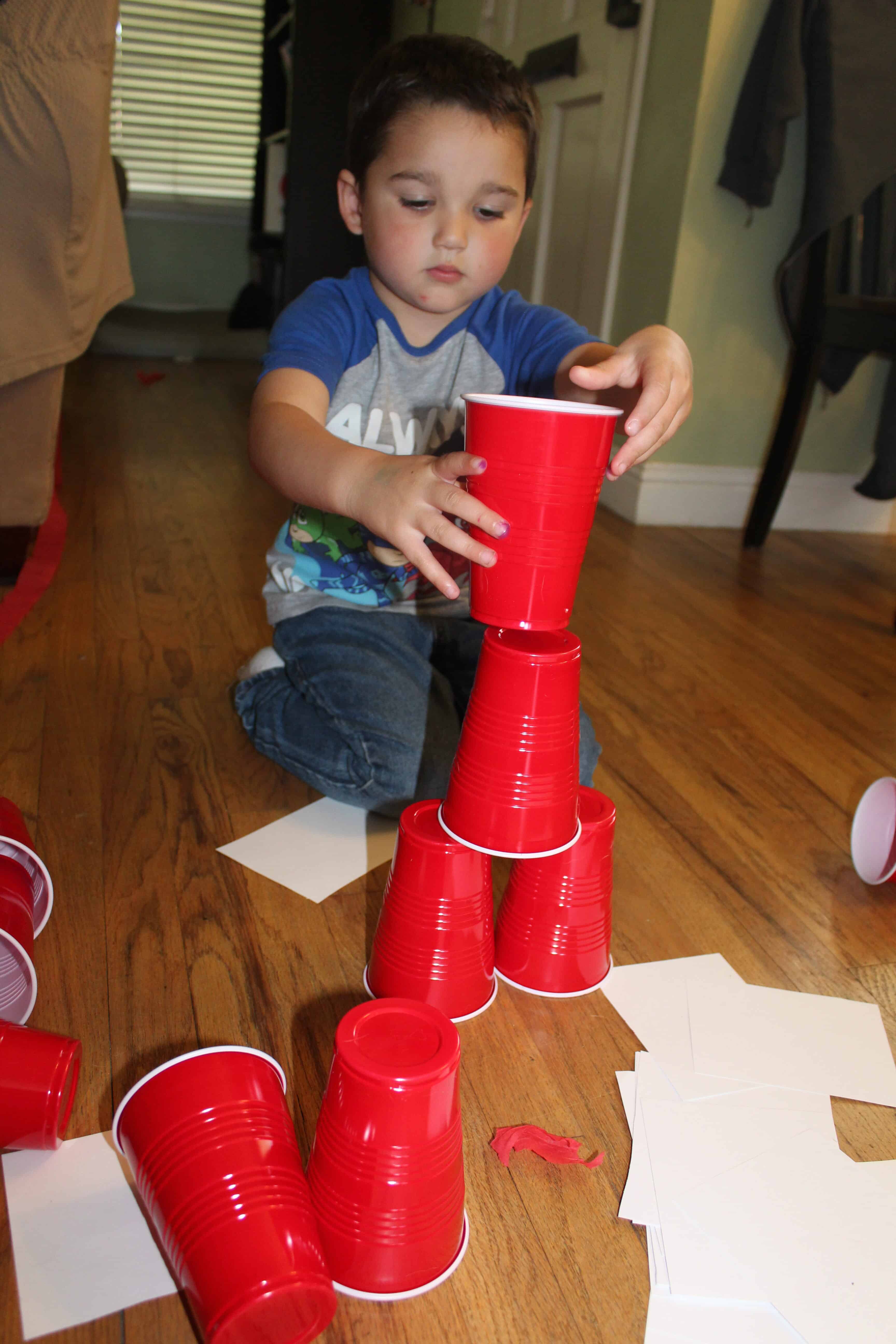 toddler building a tower of red solo cups