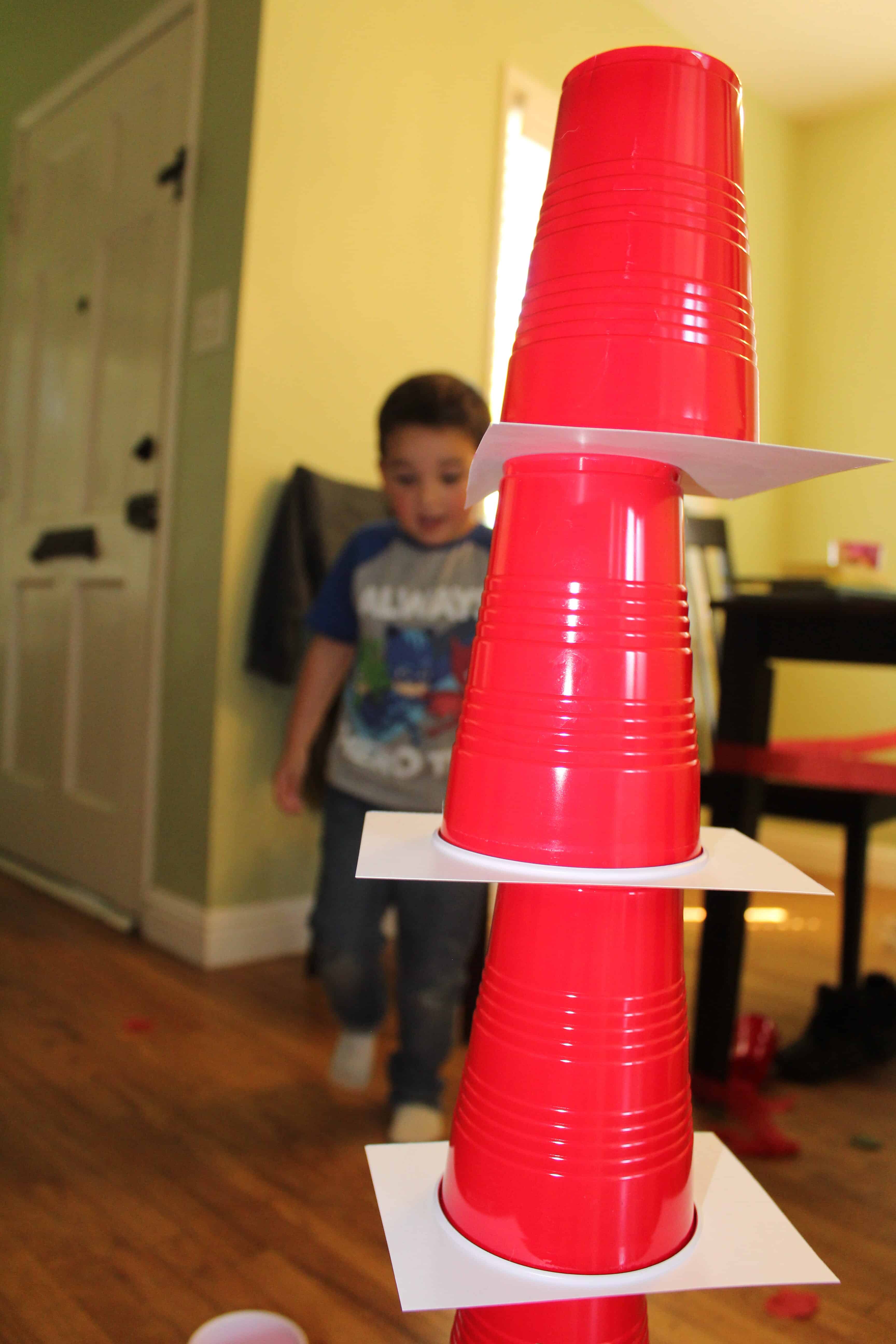 toddler engineering a tower of red solo cups