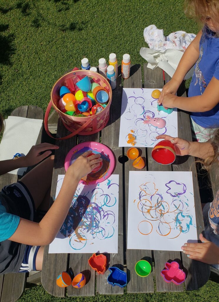 Small children using plastic easter eggs as paint stamps to create Easter Egg art