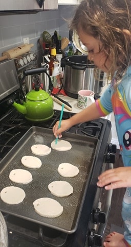 Oval shaped plain dough ornaments on a baking sheet with a straw poking holes 