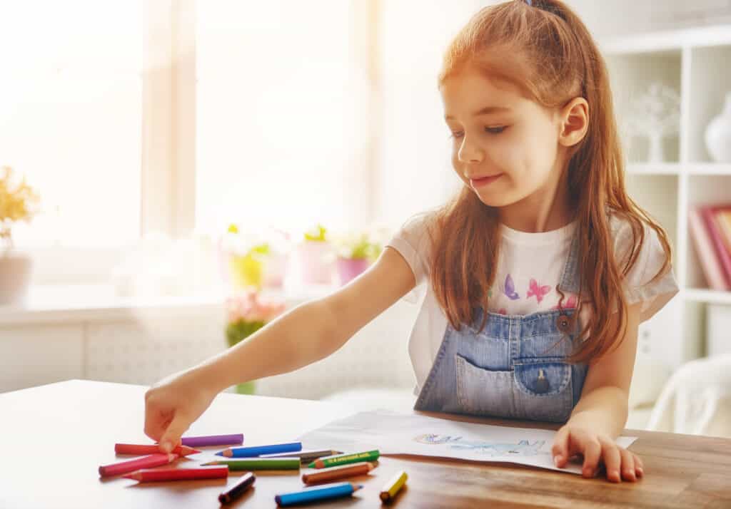 Preschool girl coloring in front of a window