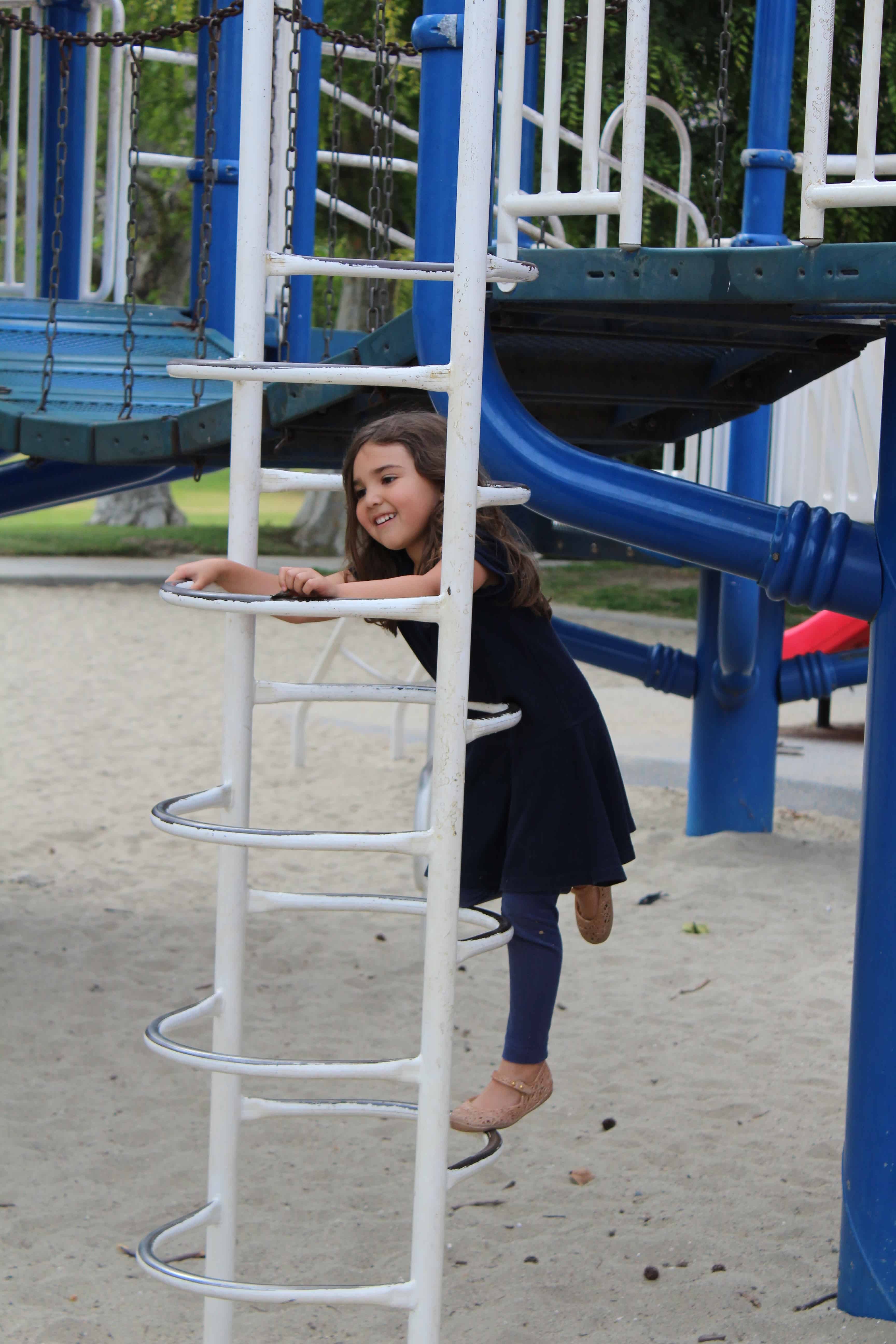 a little girl climbing a ladder at the park