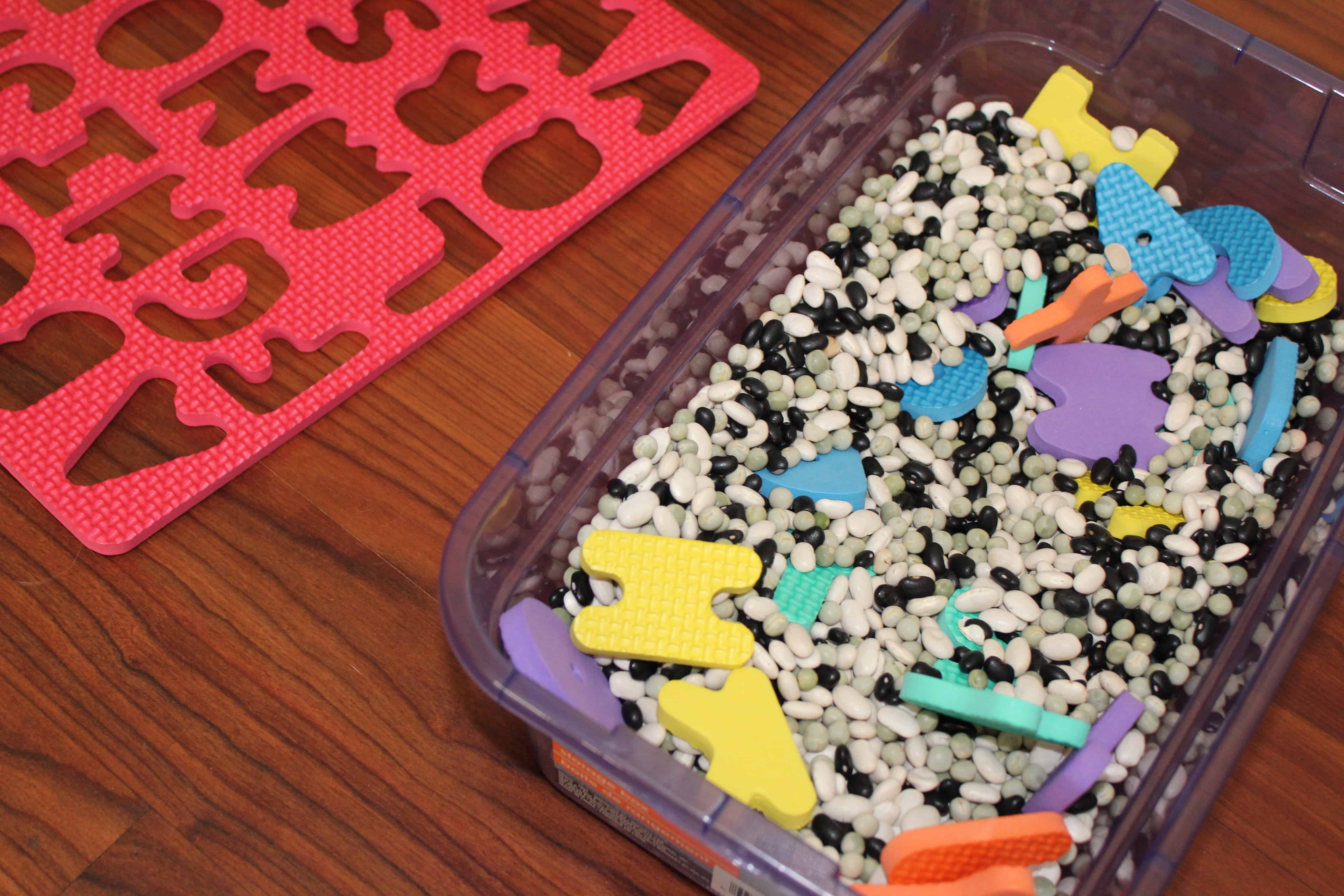 sensory bin filled with beans and foam ABC puzzle pieces