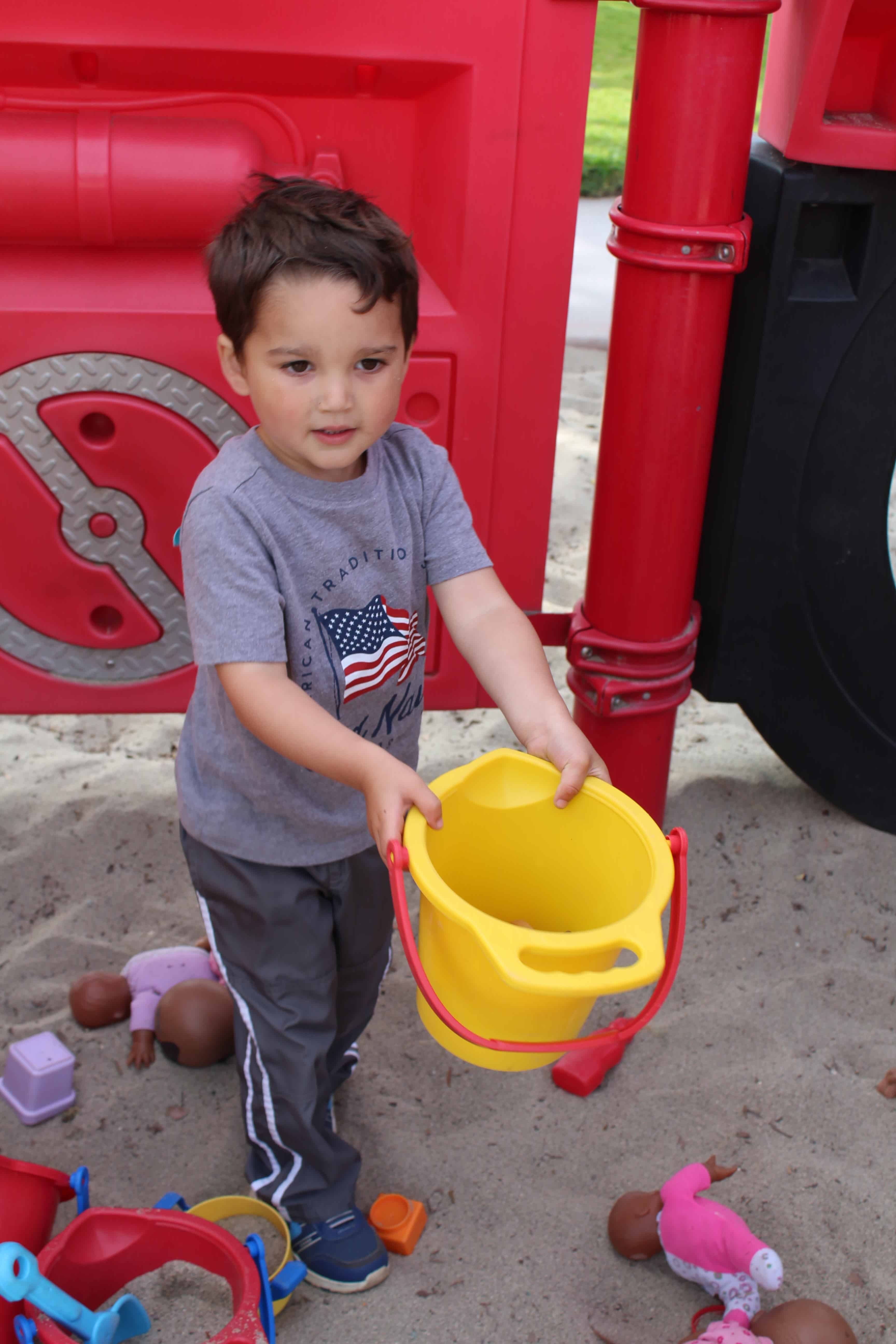 Toddler holding empty bucket.