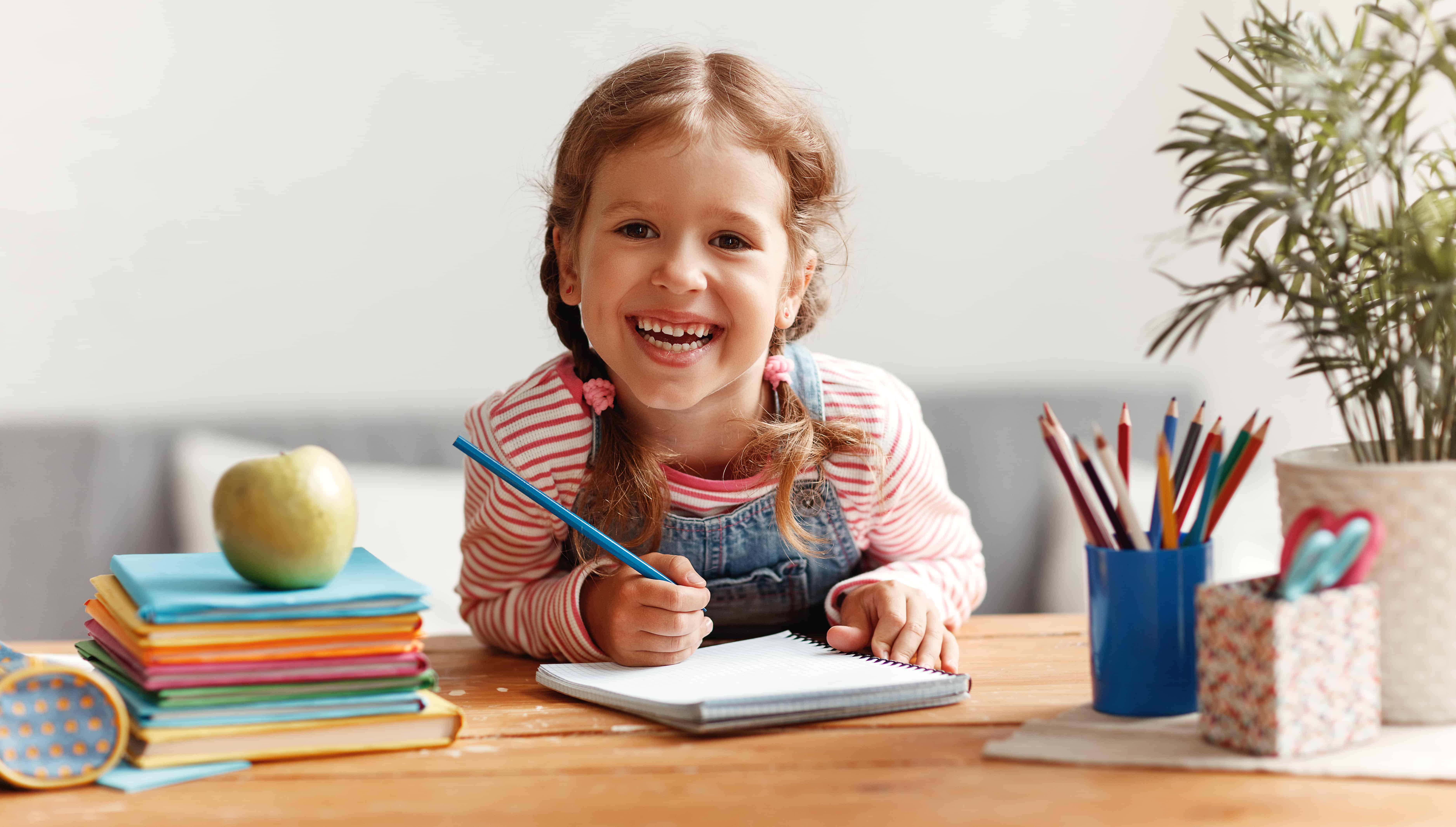 little girl smiling and writing in a notebook