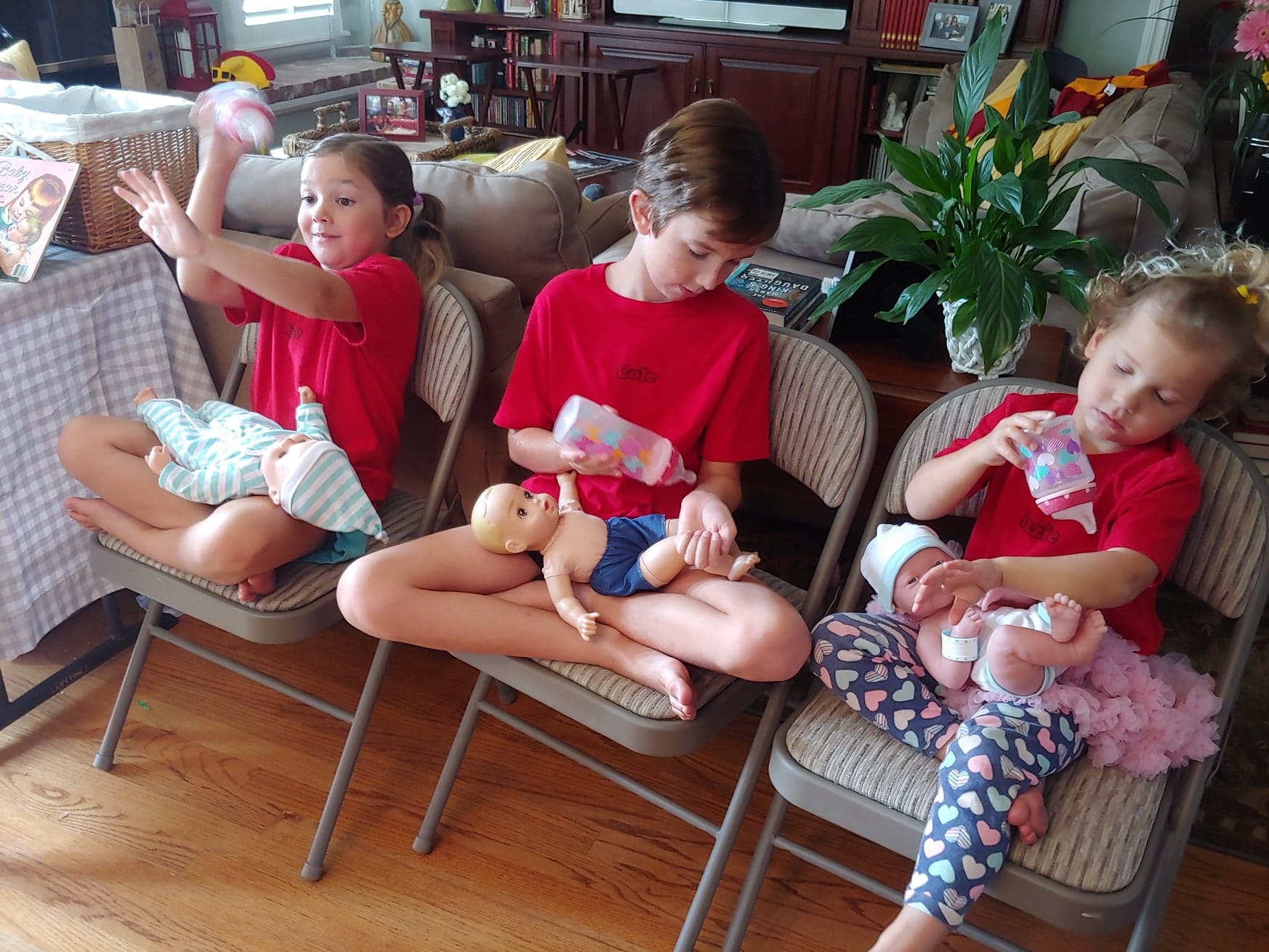 older siblings practicing with baby dolls