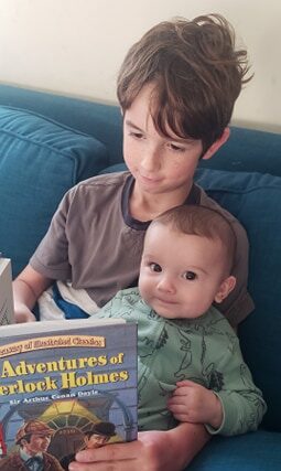 big brother reading to his baby brother