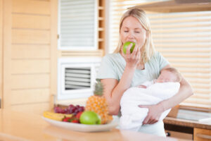 woman holding a baby and eating an apple