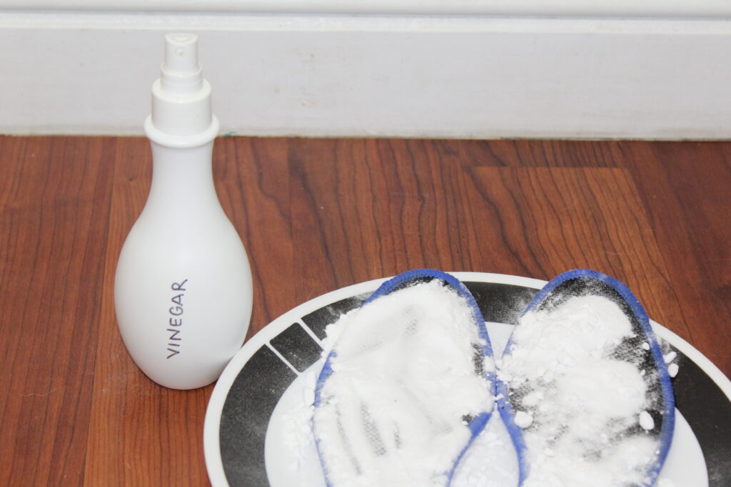 insoles covered in baking soda, sprayed with vinegar