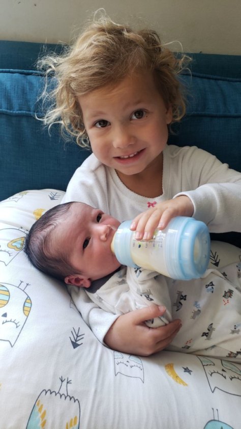 toddler feeding her baby brother