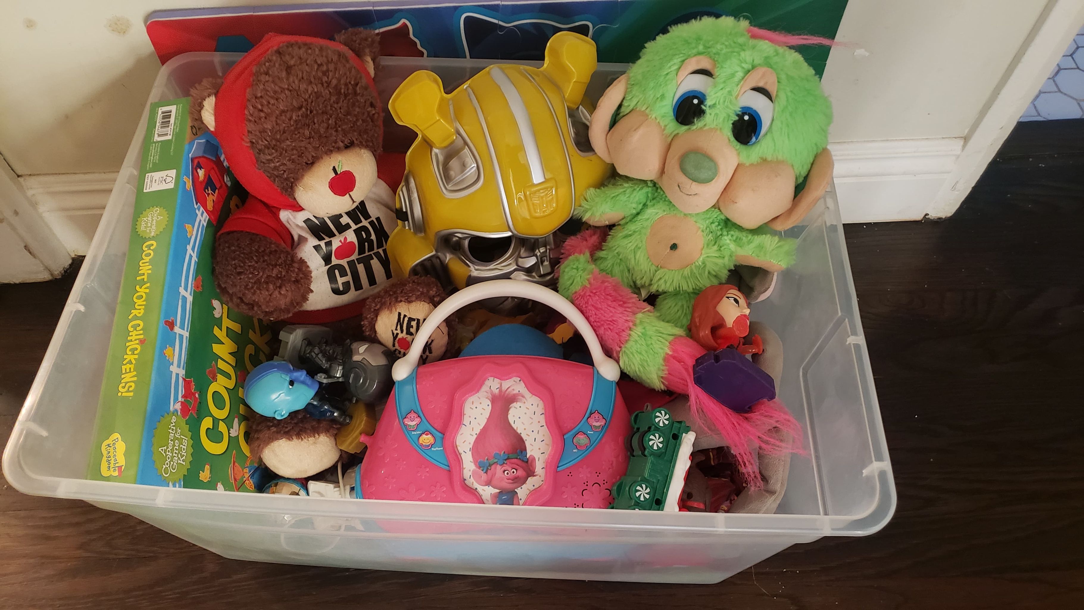 A plastic bin full of old toys to be given away. 