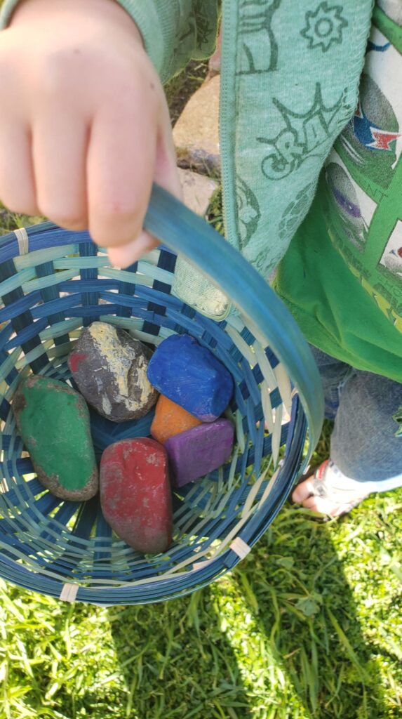 toddler holding basket of rainbow rocks