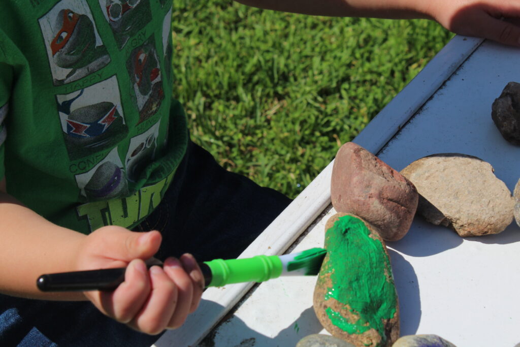 toddler painting a rock green