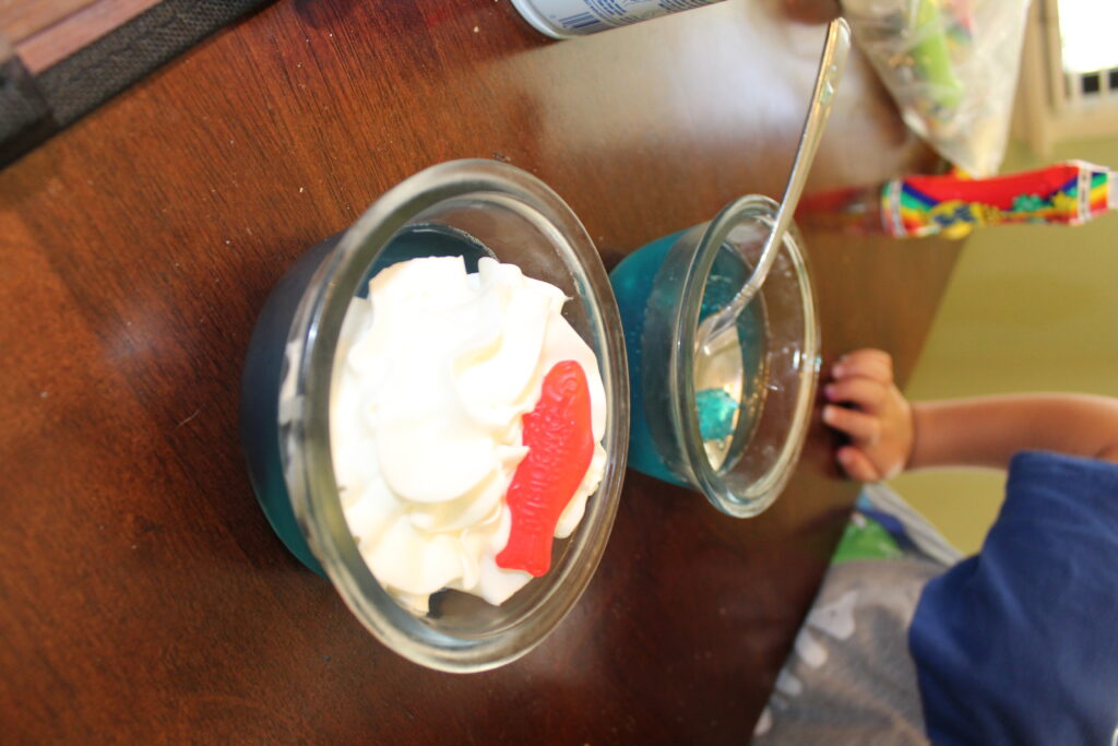 blue jello cups with whipped cream and swedish fish