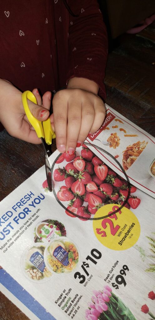 preschooler cutting practice using grocery ad