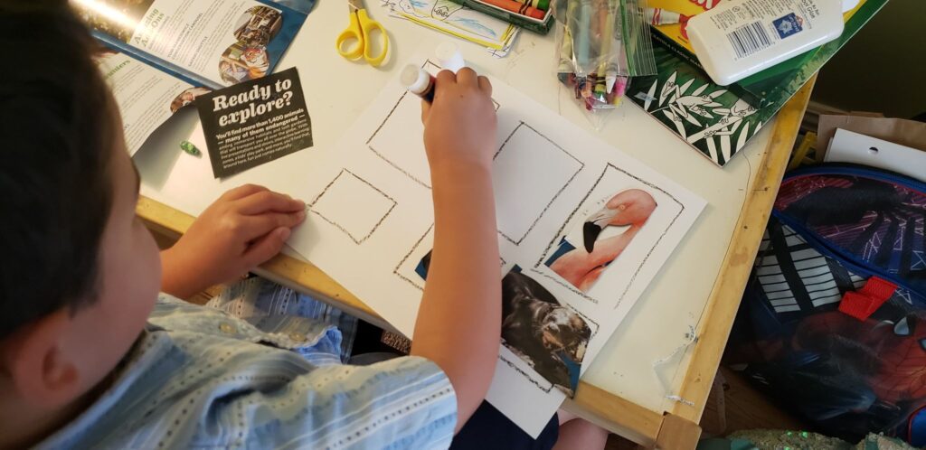 toddler gluing animals onto paper zoo