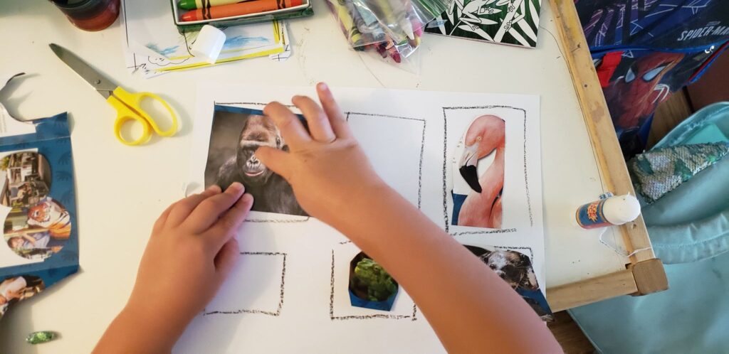 toddler gluing cut out animals onto paper