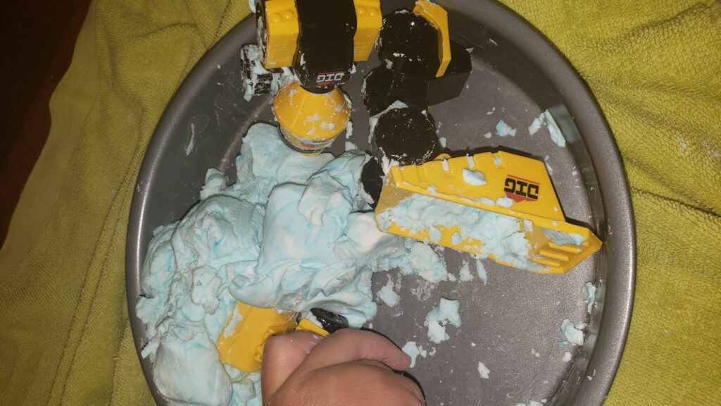 kid playing with construction trucks in playdough