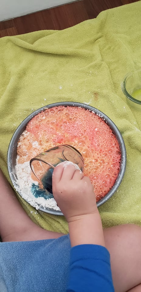 kid pouring vinegar into baking soda