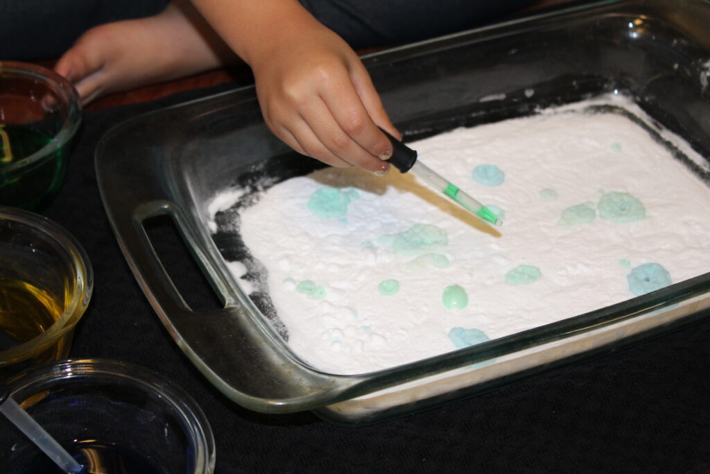 child dripping vinegar into baking soda