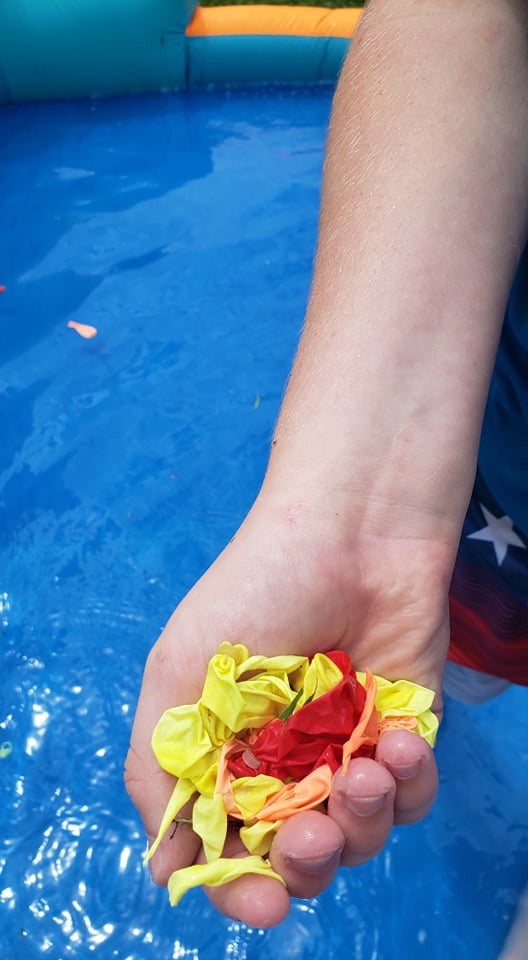 child holding broken water balloon pieces