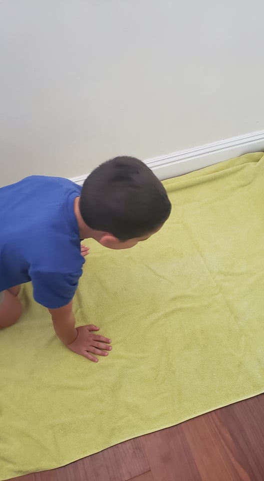 child setting up a towel for his sensory bin