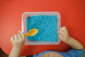 toddler playing with dryed dyed rice