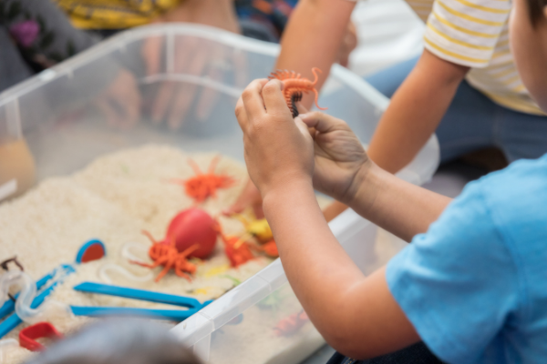 toddlers playing with toy insect sensory bin