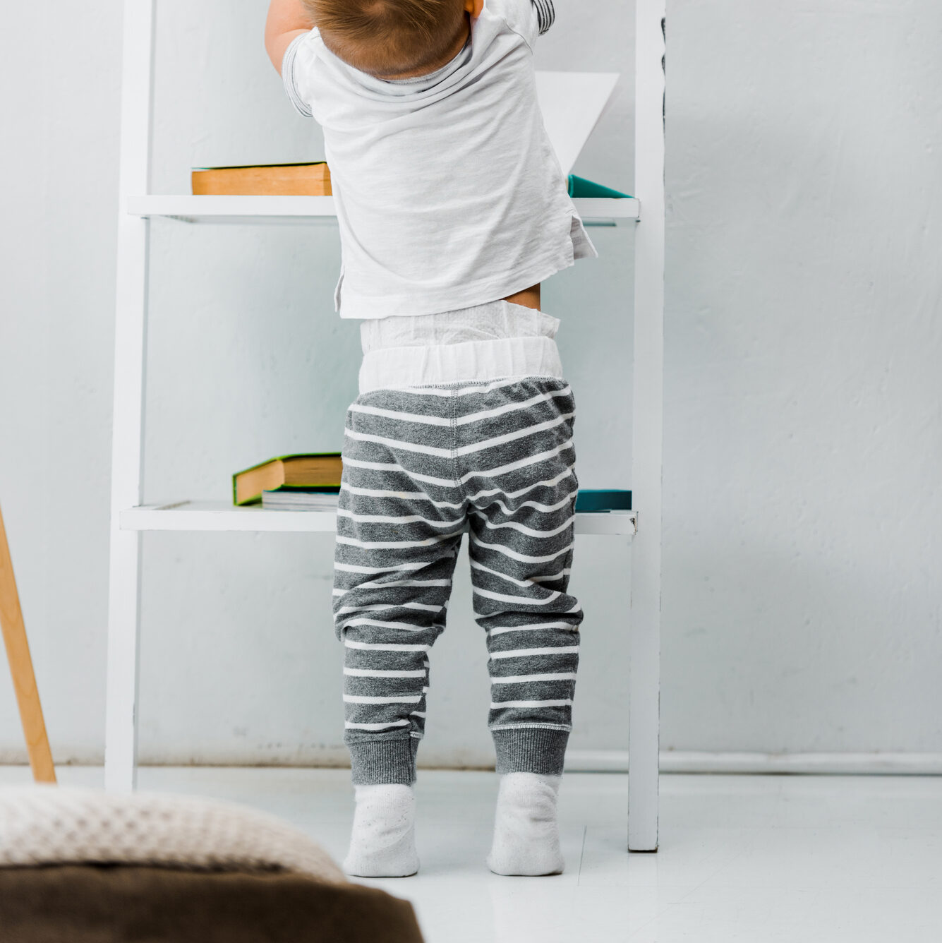 Little boy reaching up to show pants over a large diaper