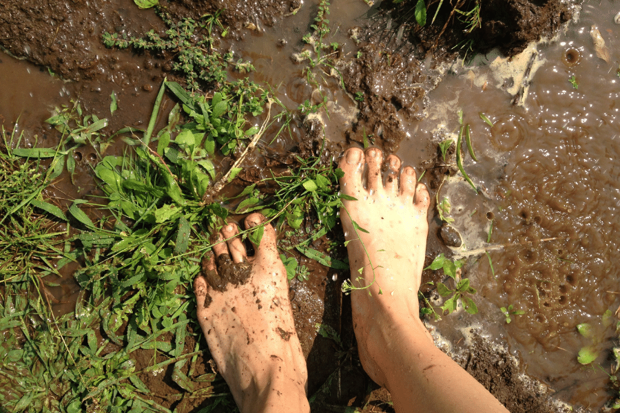 child barefoot in the mud